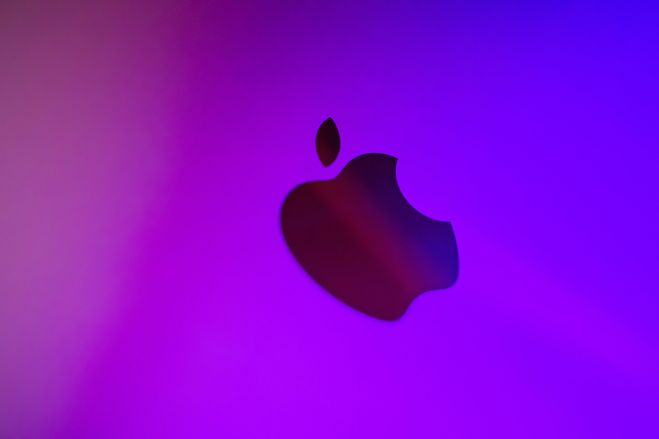 A vibrant abstract image featuring a silhouette of an apple against a purple background.